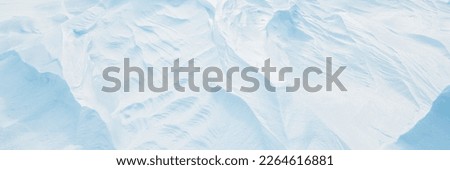 Wide panoramic winter background with snowy ground. Natural snow texture. Wind sculpted patterns on snow surface. Arctic, Polar region. Royalty-Free Stock Photo #2264616881