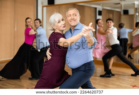 Active elderly pair practicing ballroom dance in training hall during dancing-classes. Pairs training ballroom dance Royalty-Free Stock Photo #2264620737