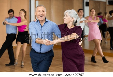 Happy older couple performing a paired ballroom dance in ballroom Royalty-Free Stock Photo #2264620757
