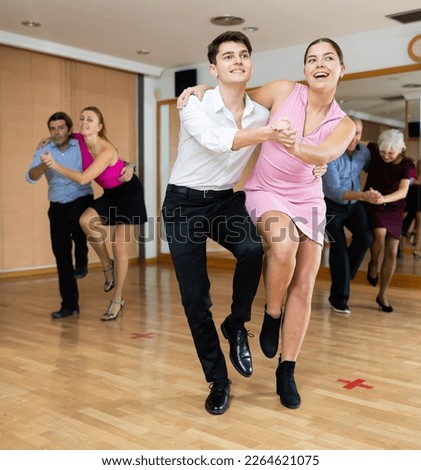 Cheerful young guy and girl practicing ballroom dances in ballroom Royalty-Free Stock Photo #2264621075