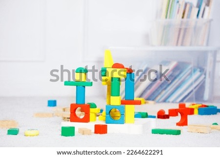 Group of toy wooden color blocks, towers build of them over boxes of toys and books around Royalty-Free Stock Photo #2264622291