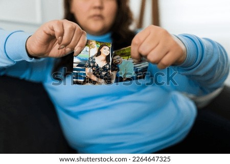 Hispanic woman breaking a photo with her partner feeling sad and upset after a heartbreaking breakup