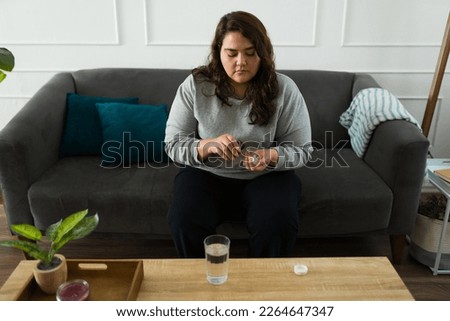 Depressed obese woman taking painkillers and suffering from substance abuse and addiction because of mental health problems Royalty-Free Stock Photo #2264647347