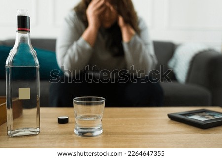 Heartbroken sad woman feeling depressed missing her ex-boyfriend drinking a bottle of alcohol at home