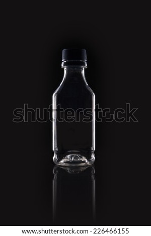A  transparent plastic empty container on the reflective bottom isolated black. 