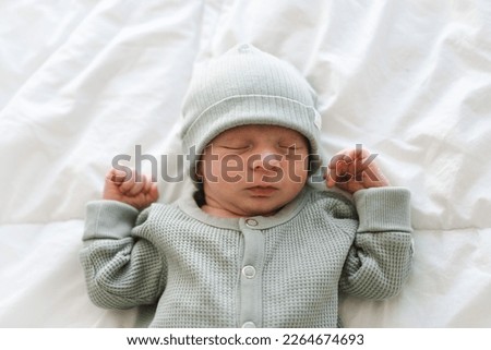 Half body shot of caucasian hairy brunet cute newborn baby sleeping wearing green crawlers and cap.One or two week old, few days child.Copy space. Royalty-Free Stock Photo #2264674693