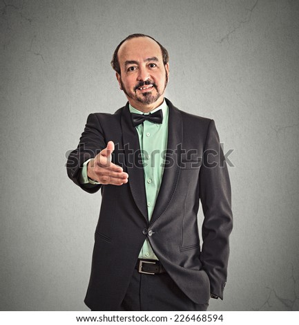 Businessman shaking hands isolated on grey office wall background. Positive face expression emotion body language 