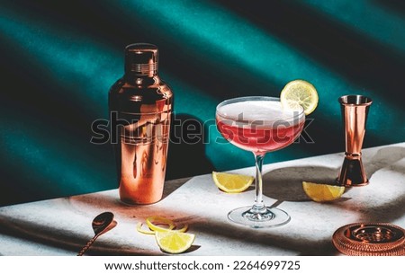 Pink lady alcoholic cocktail drink with gin, grenadine syrup, lemon juice and egg white, dark green background, bright hard light and shadow pattern Royalty-Free Stock Photo #2264699725