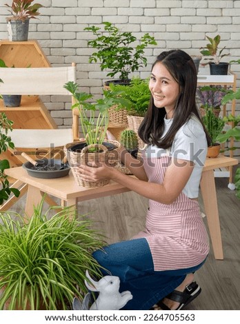 Portrait garden beautiful pretty young Asian girl woman wearing white blouse with long black hair and smile fresh with bright smile  look pot small tree leaf green plant in room shop Happy and relax