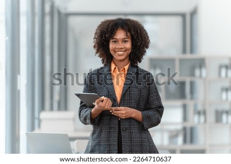 Using tablet pc, Young pretty african american business woman bookkeepers working with balance sheet yearly reports to calculate tax and online consult in modern office. Royalty-Free Stock Photo #2264710637