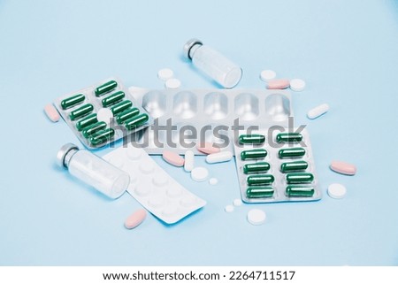 Medical pills in blisters and ampoules with antibiotics on a blue paper background. Concept of importance of treatment of chronic diseases.