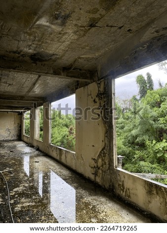 The corridor of the old hotel was shabby and left behind, filled with puddles and surrounded by forests.