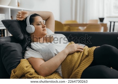 Beautiful Caucasian overweight woman rests on the sofa
