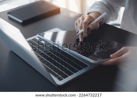 Business woman using digital tablet, finger touching on screen and working on laptop computer, surfing internet on office table, online working, business and technology, internet network, E-learning