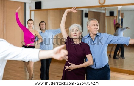 Active elderly pair practicing ballroom dance in training hall during dancing-classes. Pairs training ballroom dance Royalty-Free Stock Photo #2264734279