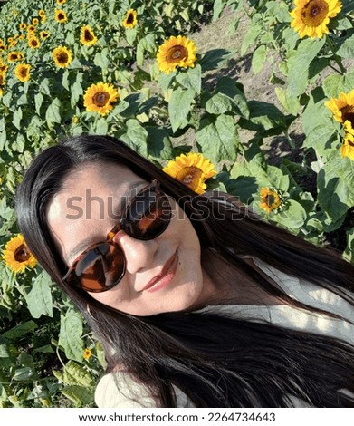 Latin adult woman with sunglasses walks through a field of sunflowers forgets her problems full of happiness in fullness, with tranquility, relaxation, calm, peace and splendor
