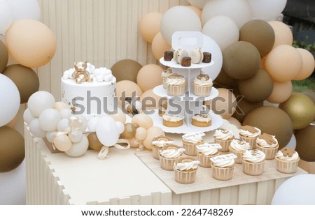 Creative gender neutral baby shower or birthday decoration in the garden. Bohemian style outdoor event set up with balloons. White cream peach caramel balloon arch kit. Sweet table for a party Royalty-Free Stock Photo #2264748269