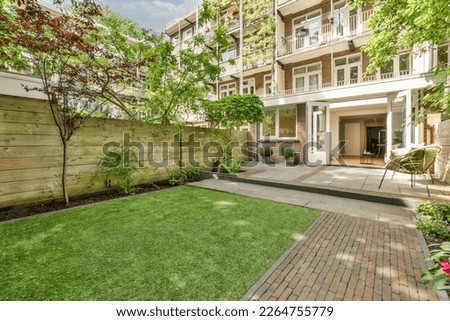 a backyard area with green grass and brick walkway leading to the front door, surrounded by lush trees on both sides