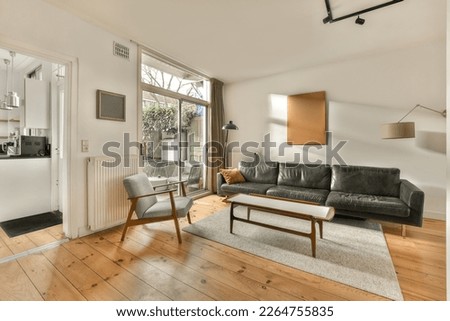 a living room with wood floors and a couch in the center of the room is an open door that leads to a patio Royalty-Free Stock Photo #2264755835