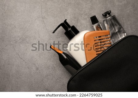 Preparation for spa. Compact toiletry bag with different cosmetic products on grey textured background, top view. Space for text Royalty-Free Stock Photo #2264759025