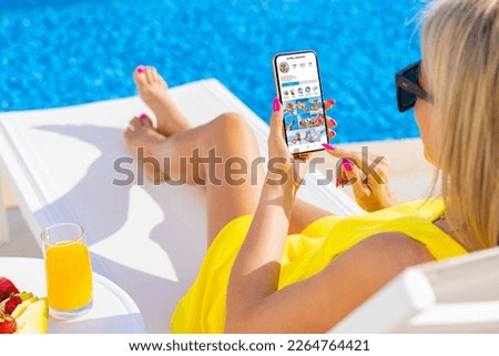 Woman viewing social media app on mobile phone while relaxing by the pool