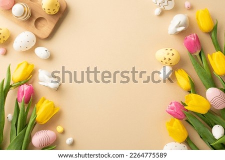 Easter decorations concept. Top view photo of colorful easter eggs ceramic easter bunnies yellow and pink tulips and wooden egg holder on isolated pastel beige background with empty space