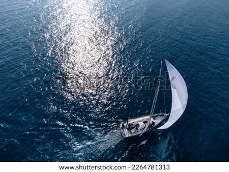 Racing sailboat sailing with white spinnaker top view Royalty-Free Stock Photo #2264781313