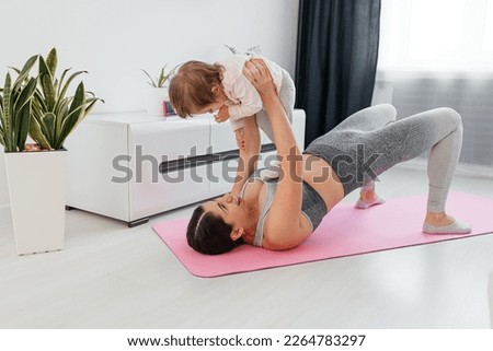 Mother and baby taking a break from working out. New mom bonding with her baby during her post-natal fitness routine. Royalty-Free Stock Photo #2264783297