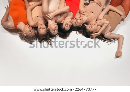 Upside down. Group of young beautiful girls in bodysuits laying on floor, posing. Femininity and acceptance. Concept of art, movement, youth, fashion, artistic lifestyle, flexibility, inspiration Royalty-Free Stock Photo #2264793777