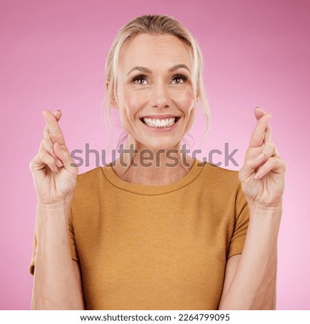 Woman, fingers crossed and smile in studio, pink background and good luck face. Excited female model hope for bonus, promotion and winning giveaway with hand emoji sign, competition prize and lottery Royalty-Free Stock Photo #2264799095