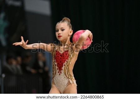 Girl doing gymnastic exercises, gymnast competition. Young gymnast girl stretching and training, emotions. Blurred background