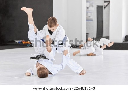 Boys, children in white kimono training, practising judo, jiu-jitsu exercises indoors. Concept of martial arts, combat sport, sport education, childhood, strength, hobby Royalty-Free Stock Photo #2264819143