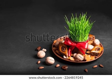 Novruz setting table decoration, wheat grass, baklava pastry and nuts on black. Nowruz arabic holiday, new year spring celebration, copy space.