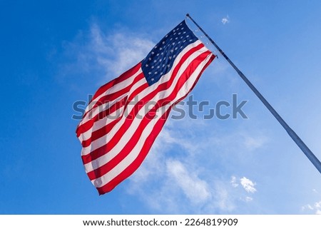 Closeup of large American flag waving in front of blue sky. US flag - American Flag waving in wind.