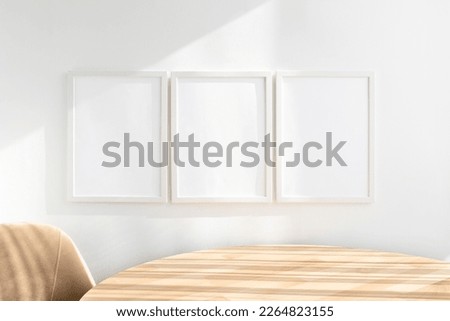 3 white frame mockups near wooden table Royalty-Free Stock Photo #2264823155