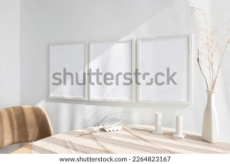 3 white frame mockups near wooden table Royalty-Free Stock Photo #2264823167