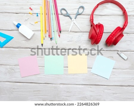 Top view musical overhead headphones with colorful stickers for text. Home office with pencils. Scissors. Copy space. Office. Desktop. Online education. Workplace background.