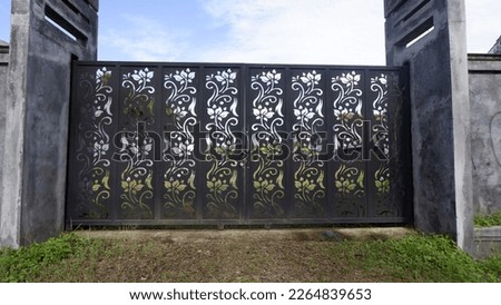photo of an iron fence of a black building with a floral motif.