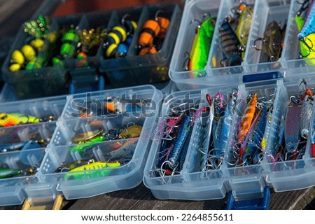 Fishing tackles and fishing baits in box .Classic Colored Fishing Lure , Beautiful Background digital image.Fishing on the lake at sunset. Royalty-Free Stock Photo #2264855611