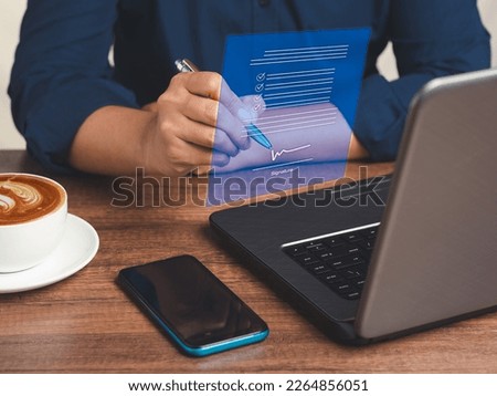 A businessman uses a pen to sign electronic documents on a virtual screen while sitting at the table in the office. Signature digital concept. Technology, document management, and paperless office