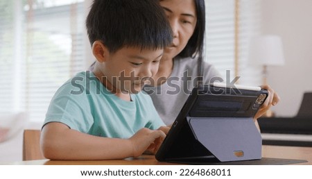 Cute asia people alpha Gen Z kid small boy play video game app online happy mum at home. Enjoy Child care fun class little son and mom study learn upskill idea course on smart digital tablet computer. Royalty-Free Stock Photo #2264868011