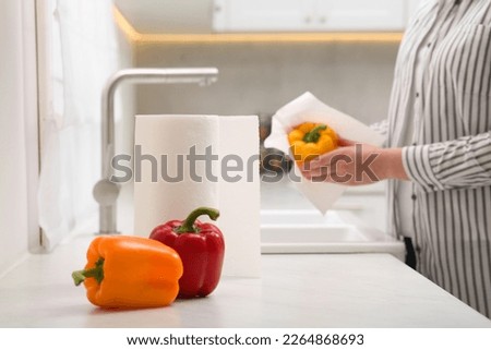 Woman wiping bell pepper with paper towel in kitchen, closeup. Space for text Royalty-Free Stock Photo #2264868693