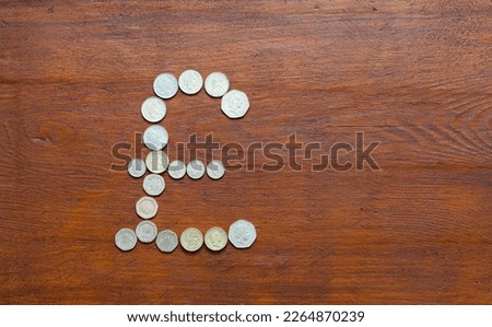 United Kingdom currency symbol Pound laid out of British pounds and pence coins on wooden background. International cooperation, money transactions, trade and finance concepts. Top view, copy space