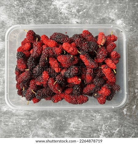 Top view of mulberry in transparent take away food plasticware and grey background