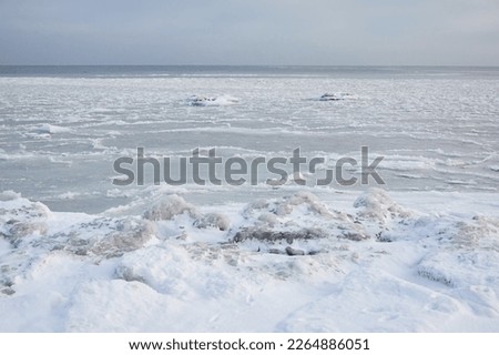 Snow-covered Baltic sea shore at sunrise.Snow, ice, frozen water. Soft sunlight. Picturesque winter scenery. Seasons, nature, environment, climate change, global warming themes Royalty-Free Stock Photo #2264886051