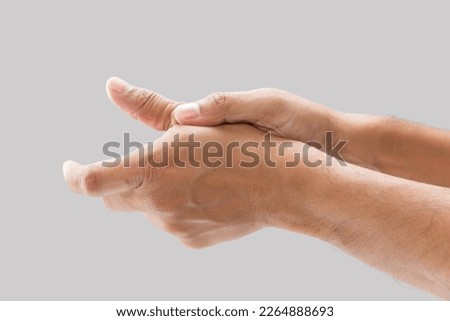 A man with thumb pain on a gray background.