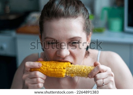 The girl greedily eats boiled corn. Yellow, bright, freshly cooked corn at home. The concept of live real photos. woman eating delicious corncob.