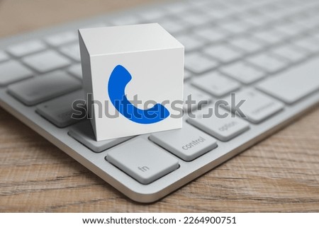 Phone icon on white block cube with modern computer keyboard on wooden table, Business contact us concept