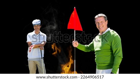 Portrait of diverse senior male golf player smiling against fire flame effect on black background. retirement sports and active senior lifestyle concept