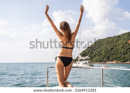 Caucasian woman in bikini looking at beautiful view during yachting. Attractive beautiful female tourist hanging out celebrate holiday vacation trip while catamaran boat sailing during summer sunset.